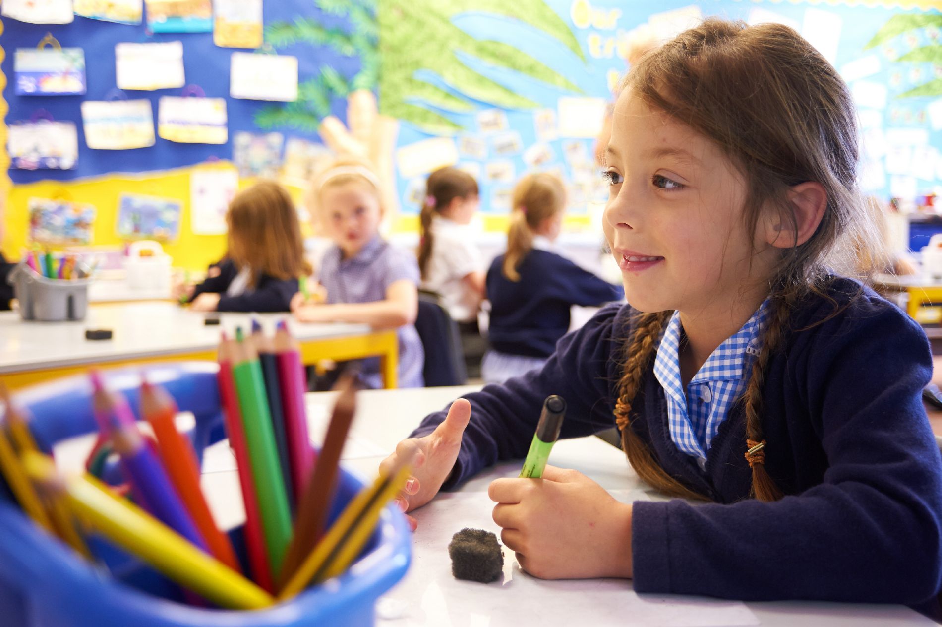 a child with long brown hair with a pen and whiteboard