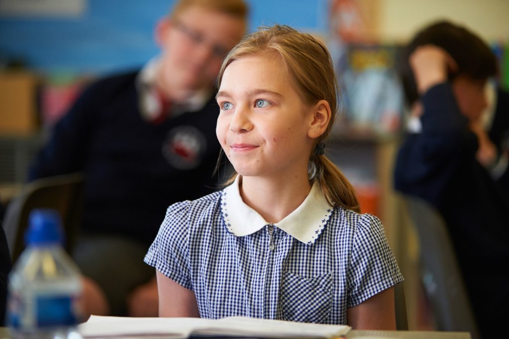 A Paddock Wood Primary Academy student is sat at a desk looking up to the front of the class.